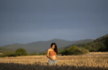 Těhotná žena stojící v poli