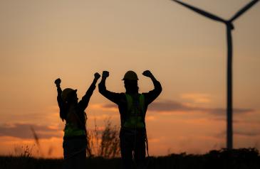 Lidé před větrnou elektrárnou v západu slunce